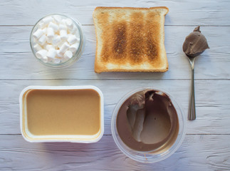 Ingredients for American Breakfast: bread toast, peanut and chocolate paste, white marshmallows. Flat lay
