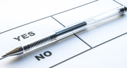 Concept: a questionnaire on white paper with a Yes or no vote and a pen. Choosing the right solution