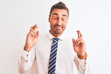 Young handsome elegant business man over isolated background gesturing finger crossed smiling with hope and eyes closed. Luck and superstitious concept.