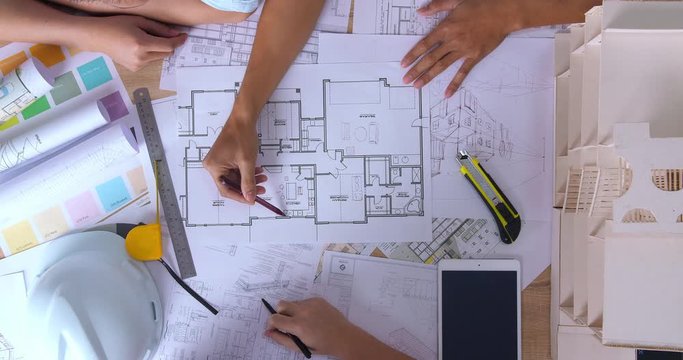 Top View Of Architects Discussing Together With Blueprint Paperwork