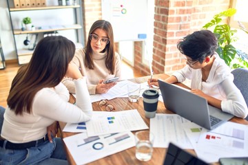 Beautiful businesswomen smiling happy. Sitting with smile on face working using smartphone and laptop at the office