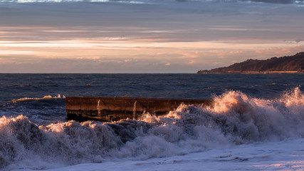 Sea sunset. Waves roll on the shore. The violence of the elements. Sea foam.