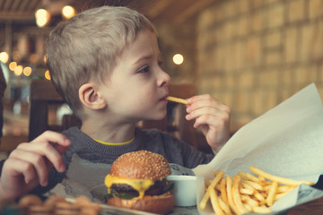 child eats a mini Burger and fries. children's menu in the cafe