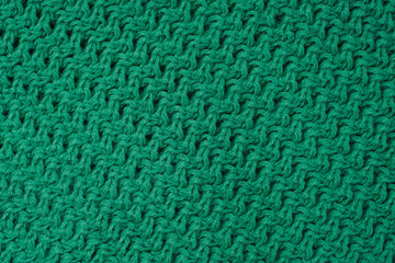 Thick binding of green threads. Netting as a backdrop. Green background of knitted wool