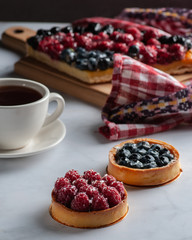 berry pies, raspberries, blueberries, and hot lemon tea. on a light table