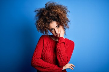 Fototapeta na wymiar Young beautiful woman with curly hair and piercing wearing casual red sweater thinking looking tired and bored with depression problems with crossed arms.