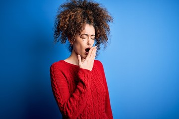 Fototapeta na wymiar Young beautiful woman with curly hair and piercing wearing casual red sweater bored yawning tired covering mouth with hand. Restless and sleepiness.