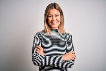 Obraz premium Young beautiful blonde woman wearing casual striped sweater over isolated background happy face smiling with crossed arms looking at the camera. Positive person.