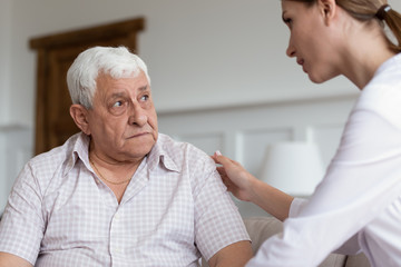 Caring female nurse comfort worried senior male patient