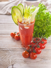 Vertical shot glass of fresh tomato juice. Juice, cucumber, celery sticks and seasonings