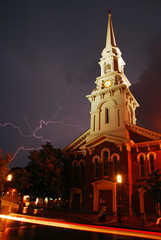 Fototapeta na wymiar Lightning streaks across the stormy skies near a historic church