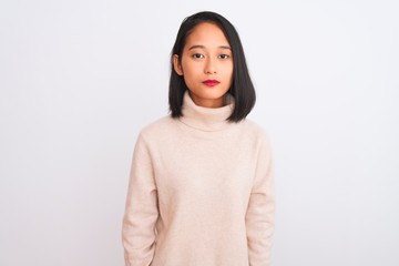 Young chinese woman wearing turtleneck sweater standing over isolated white background Relaxed with serious expression on face. Simple and natural looking at the camera.