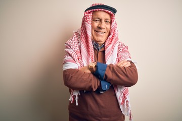 Senior handsome arab man wearing keffiyeh standing over isolated white background happy face smiling with crossed arms looking at the camera. Positive person.