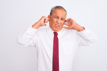 Senior grey-haired businessman wearing elegant tie over isolated white background covering ears with fingers with annoyed expression for the noise of loud music. Deaf concept.