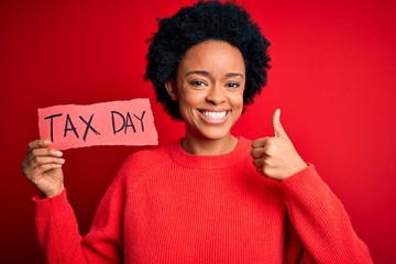 Young African American afro woman with curly hair holding paper with tax day message happy with big...