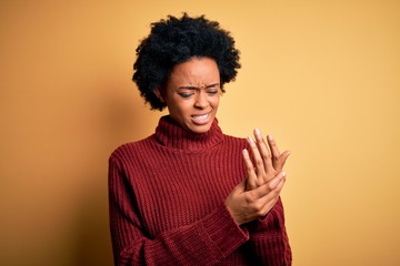 Young beautiful African American afro woman with curly hair wearing casual turtleneck sweater Suffering pain on hands and fingers, arthritis inflammation