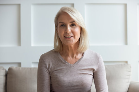 Headshot portrait of mature woman sit on couch talking