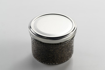 Black caviar in a jar on a neutral background