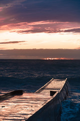 Big waves breaking on a stone pier in stormy weather with a bright sunset, a big tide. Black Sea. Sochi, February.