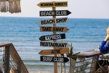 Direction signpost on sea background. Wooden pointer to the beach, Surf club, Shop, ATM.