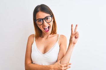 Beautiful redhead woman wearing glasses over isolated background smiling with happy face winking at the camera doing victory sign. Number two.