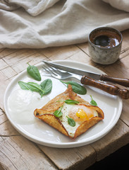 Breton buckwheat crepes with egg, spinach and cream, filed with the coffee. Rustic style.