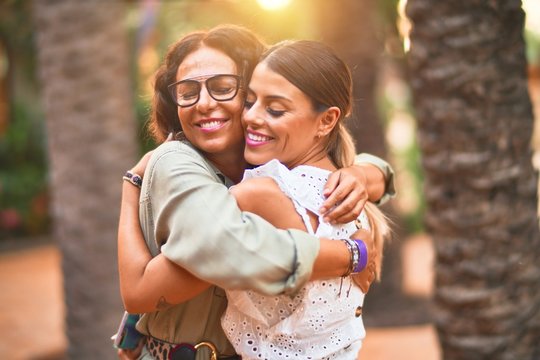 Beautiful mother and daughter smiling happy and confident. Standing with smile on face hugging at town park