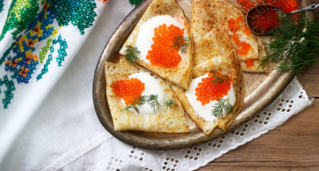 Homemade pancakes with red caviar, sour cream and dill served with vodka. Rustic style.