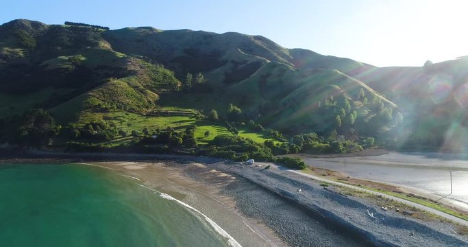 4k forward tracking with morning sun lens flare aerial of the natural boulder barrier causeway beside the sea connecting Pepin island with south island at Cable Bay,Rotokura,South Island New Zealand