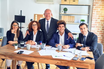 Group of business workers smiling happy and confident in a meeting. The boss standing and employees sitting with smile on face looking at the camera at the office