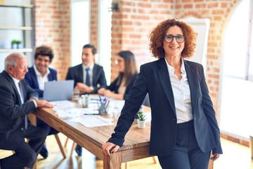 Group of business workers smiling happy and confident working together in a meeting. One of them, standing with smile on face looking at camera at the office.