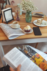 Girl reading a magazine in front of a table with different desserts