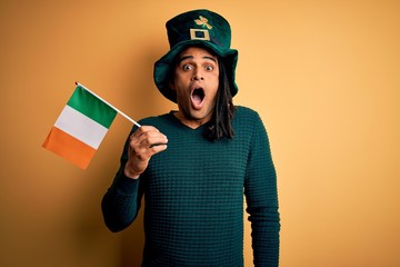 African american man wearing green hat holding irish ireland flag celebrating saint patricks day...