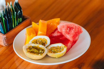 Tasty exotic fruits - ripe passion fruit, mango on breakfast at outdoor restaraunt