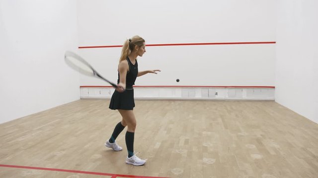 A young attractive woman playing squash on court, slow motion