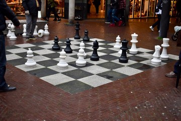 People are playing chess on the big size chess board on the street