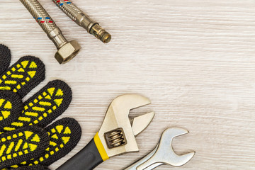 Plumbing equipment repair tools adjustable wrench and hoses, gloves, flexible connection on bright...