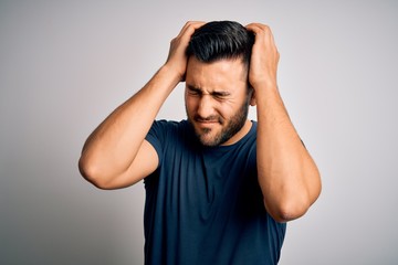 Young handsome man wearing casual t-shirt standing over isolated white background suffering from headache desperate and stressed because pain and migraine. Hands on head.