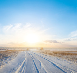 beautiful winter snowbound plain with road to sunset