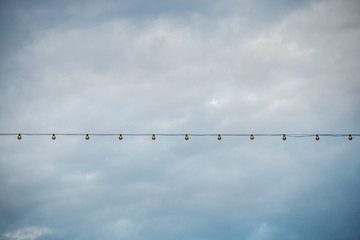 Line of lightbulbs in a cloudy sky