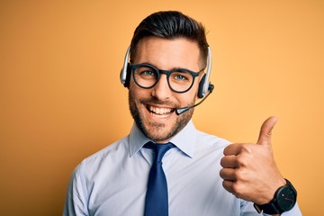 Young business operator man wearing customer service headset from call center doing happy thumbs up...