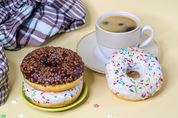 trend in food. top view on stack of donuts, doughnut with chocolate and white icing, and aromatic coffee espresso, americano on yellow background clouse up