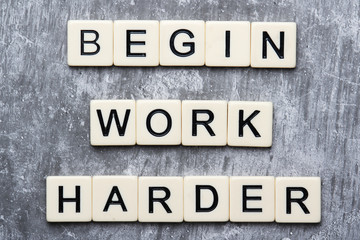 The motivating slogan Work Harder formed with tile letters	