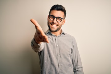 Young handsome man wearing elegant shirt and glasses over isolated white background smiling...