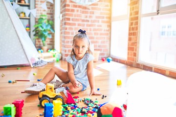 Young beautiful blonde girl kid enjoying play school with toys at kindergarten, smiling happy playing with building blocks at home