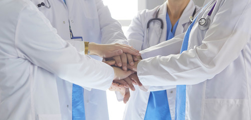 Team of medical workers holding hands together indoors, above view. Unity concept