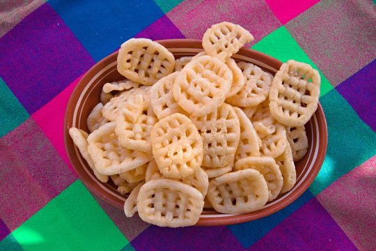 Plate full with Duros also known as churritos a Mexican snack food made of deep fried puffed wheat, on a colorful Mexican tablecloth