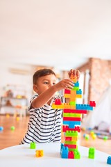 Beautiful toddler boy playing with construction blocks at kindergarten