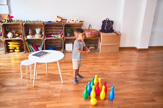 Beautiful toddler boy playing bowling at kindergarten