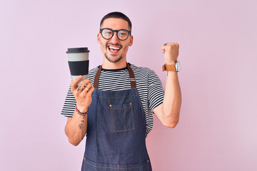 Young handsome barista man wearing uniform over isolated background screaming proud and celebrating...